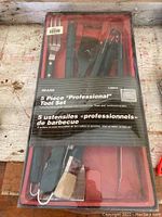 Full view of boxed 5 piece barbecue tool set with red case cover showing utensils inside