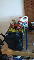 Photo of lot showing carrying bag with yellow tow rope, funnel, WD-40 spray, Rain-X bottle, and antifreeze jug on a workbench