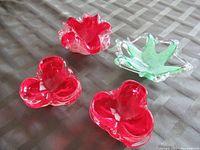 Four small glass bowls on a checkered tablecloth, showing red heart shapes and clear green star-shaped bowl