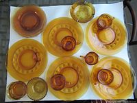 Top view of assorted amber glass cups on saucers and plates, arranged on white background.