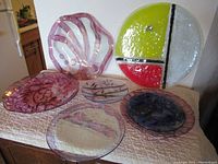 Six assorted vintage art glass dishes on a table, showing various colors and shapes