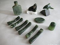 Full view of the jade collection including flask, walrus and dolphin figurines, curved jade pieces, oval jade stone, and thimble.