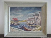 Front view of framed oil painting depicting a maritime scene with boats and buildings near water under a cloudy sky.