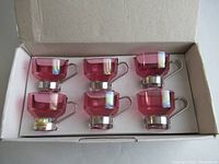 Six pink glass espresso cups with silver metal holders in white box.