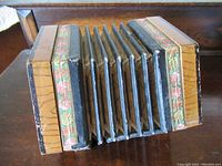 Top-down side view showing worn black pleated bellows between painted wooden sides with floral trim