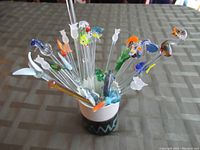 View of all glass swizzle sticks arranged in ceramic mug, showing color and animal designs
