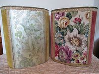 Front view of two vintage Italian style decorative bins showing distinct floral fabric panels and velvet sides in mustard yellow and rust colors.