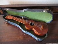 Ukulele placed inside open hard case showing the full instrument with case interior