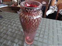 Full view of the purple and gold glass vase on a table, showing overall shape and color.