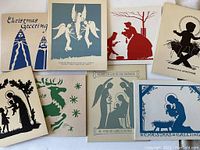 Photo showing an assortment of vintage 1920s Christmas cards with various religious and festive silhouette designs, arranged on a flat surface.