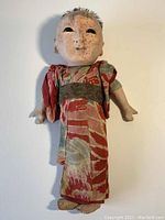 Full body image of antique style Japanese doll dressed in traditional red kimono with patterned design.