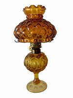 Full side view of the amber glass kerosene lamp showing hobnail patterned shade with ruffle edge and decorative base.
