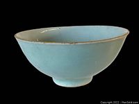 Side view of the light blue deep footed Japanese porcelain bowl showing its shape and rim condition.