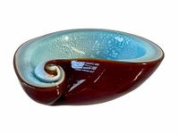 Side angle view showing curved swirl shape with glossy brown outer surface and textured blue inner surface