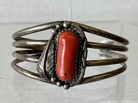 Front view of sterling silver coral cuff bracelet showing red coral centerpiece with silver leaf and bead accents.