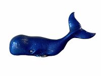 Side view of the blue painted metal whale figurine showing the whale's shape and tail detail.