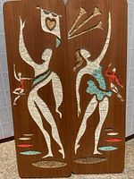Front view of both wooden panels showing the stylized carved and painted ballet dancers on a warm wood background.
