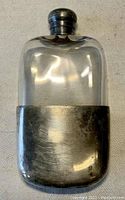 Clear view of the antique glass flask with silver-plated casing and stopper, showing the front side.