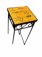 View of small side table showing bird and leaf design on yellow-orange pottery tile top and black metal frame with decorative curls.