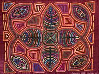 Close-up photo of one of the Kuna Mola fabric panels showing a detailed symmetrical fern-like design in multiple colors on maroon background.