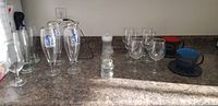 Photo of beer glasses, wine glasses, baby bottles, tea cups with saucers on countertop