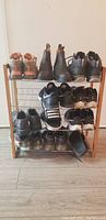 Front view of a wooden shoe rack holding multiple pairs of shoes on three metal wire shelves.