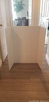 Photo of white foam poster board tri-fold display set up indoors showing three panels and its size.
