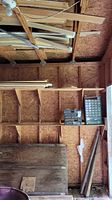 Photo showing scrap wood planks stored along wall and rafters of a shed