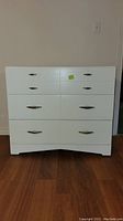 Front view of white 3-drawer dresser with metal handles and visible wear marks