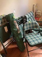 Overview of all lawn and folding chairs showing the lawn chair in green bag, two chaise loungers, and padded card table chairs.