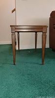 Front view of one wooden side table showing carved decoration on legs and trim details