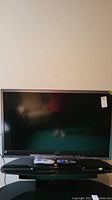 Front view of Sony 46 inch flat screen TV showing screen and stand with two remotes on it.
