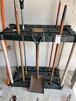 Front view of the gardening tool stand with some garden tools placed to show how it holds them.