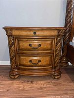 Front view of nightstand with three drawers and carved columns