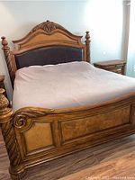 Front angled view of carved wooden bed frame showing headboard and footboard