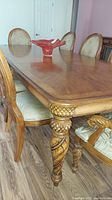 Close-up photo of the dining table corner showing carved legs and polished wood top.