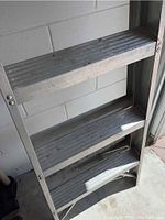 Close-up of the ladder's steps showing aluminum ridged steps and visible signs of wear.