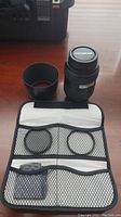 Olympus 40-150mm lens with lens hood and filter case on table