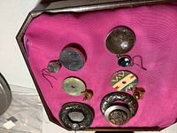 Photo of four pairs of round earrings displayed on pink fabric showing various sizes and designs including mesh, Paua shell, silver tone, and blue crystal elements.