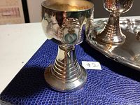Close-up of a silver-plated shot glass with Royal Canadian Air Force emblem on blue background