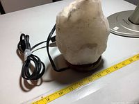 Clear crystal rock lamp with black electrical cord and wooden base against a white background. Lamp measures about 8 inches tall.