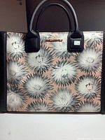 Front view of Karl Lagerfeld handbag with peach pink floral pattern and black handles, showing logo and overall design.