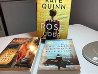 Photo of three Kate Quinn books: The Rose Code with a woman in a yellow background, The Alice Network with a WWII image, and Lady of the Eternal City with Roman themed cover.