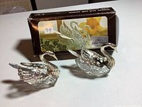 Two silver plated swan salt and pepper shakers with glass bodies, displayed with original box showing swan image and silver-plated label