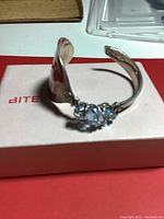 Sterling silver spoon bracelet with blue stones on a white box