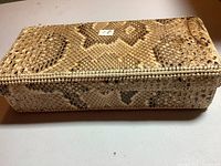 Top and side view of rectangular snakeskin pencil box showing textured scale pattern and rectangular shape with measuring tape indicating length about 10 inches