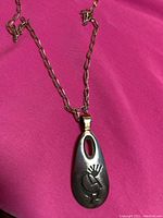 Photo showing sterling silver chain attached to pendant with engraved Kokopelli design on pendant