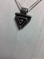 Front view of sterling silver triangular maze pendant hanging from the chain showing detailed geometric design.