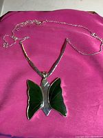 Full view of the 22-inch sterling silver chain with jade butterfly pendant, showing chain length, pendant body and wings detail on pink fabric background.