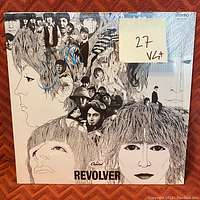 Front cover of The Beatles 'Revolver' album showing original illustrated cover art. Note with grading '27 VG+' and pen markings visible on the sleeve.